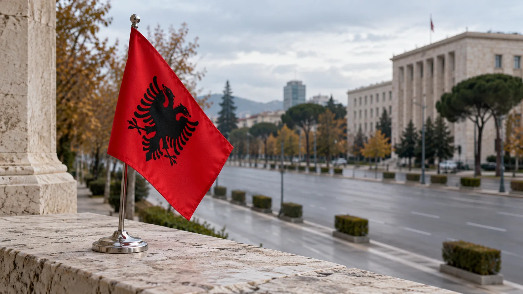 Albanian flag on a stone ledge with an urban street and building in the background